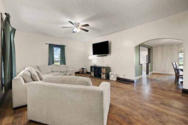 living room featuring dark hardwood / wood-style floors, a textured ceiling, and ceiling fan