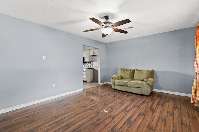 sitting room featuring dark wood-type flooring, a textured ceiling, and ceiling fan