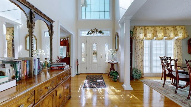 entryway with ornate columns, light wood-type flooring, and a healthy amount of sunlight