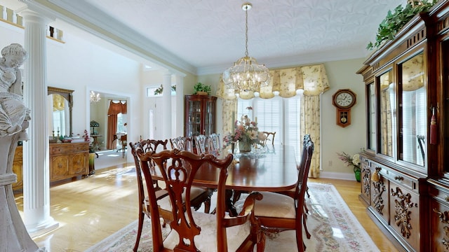 dining area featuring a notable chandelier, ornate columns, ornamental molding, and light wood-type flooring