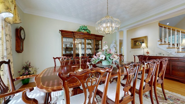 dining room with decorative columns, light hardwood / wood-style floors, ornamental molding, and a chandelier