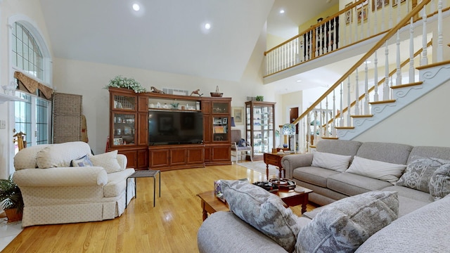 living room featuring high vaulted ceiling and light hardwood / wood-style flooring