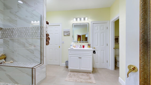 bathroom featuring vanity, toilet, tile patterned floors, and tiled shower