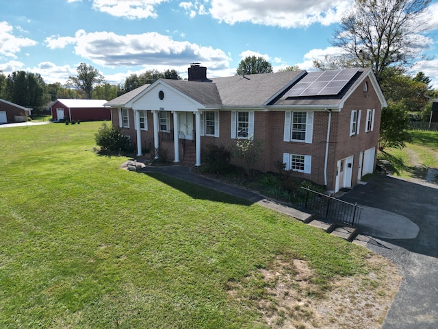 view of front of home featuring solar panels, covered porch, a front yard, and a garage