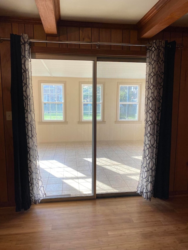 doorway to outside with light hardwood / wood-style flooring, beam ceiling, and a wealth of natural light