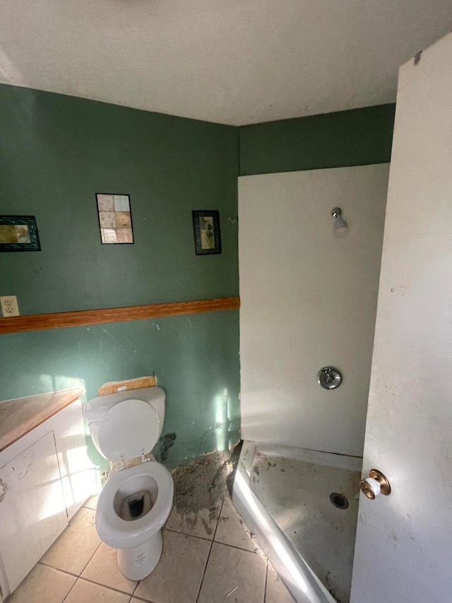 bathroom with walk in shower, toilet, and tile patterned floors