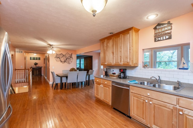 kitchen with decorative backsplash, a textured ceiling, sink, light hardwood / wood-style floors, and stainless steel appliances