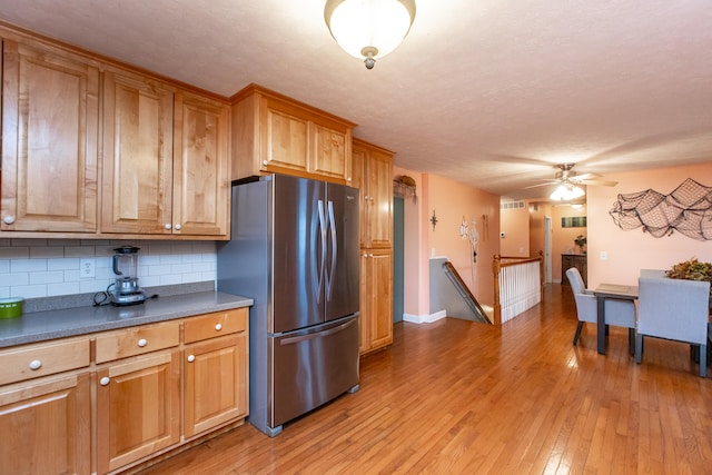 kitchen featuring stainless steel fridge, tasteful backsplash, light wood-type flooring, a textured ceiling, and ceiling fan