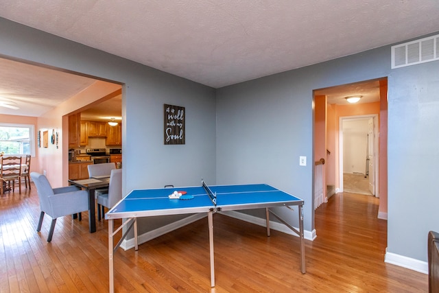 game room featuring light hardwood / wood-style flooring and a textured ceiling