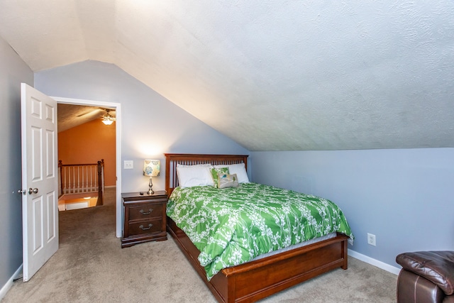 bedroom featuring a textured ceiling, light colored carpet, and vaulted ceiling