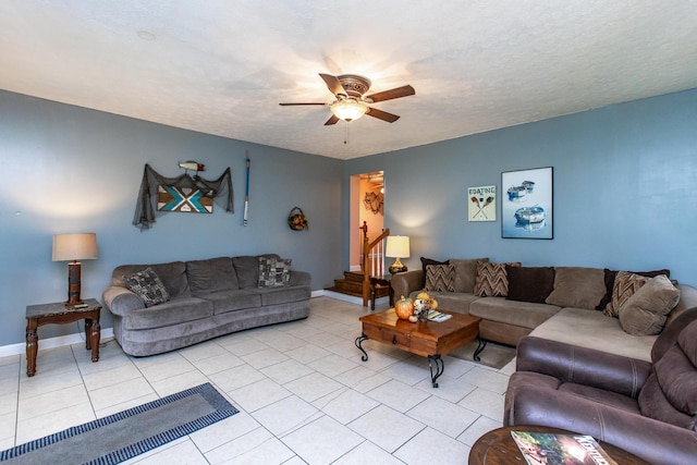 living room featuring a textured ceiling, light tile patterned floors, and ceiling fan