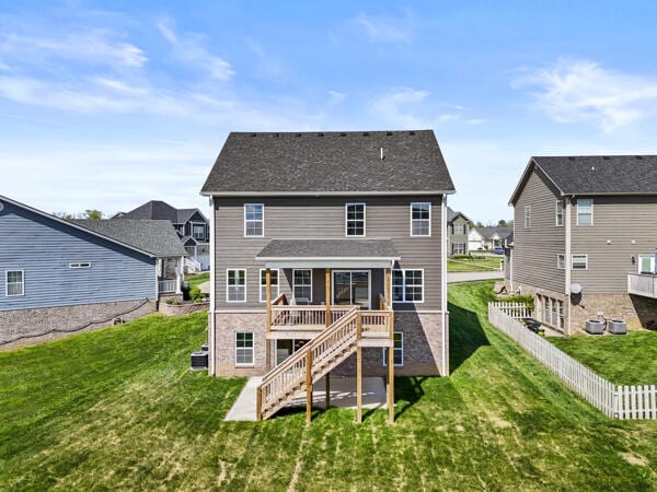 back of property with a residential view, a lawn, stairway, and fence