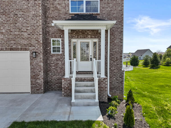 property entrance featuring a yard and brick siding