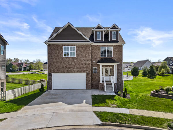view of front of property with a front yard, a garage, driveway, brick siding, and fence