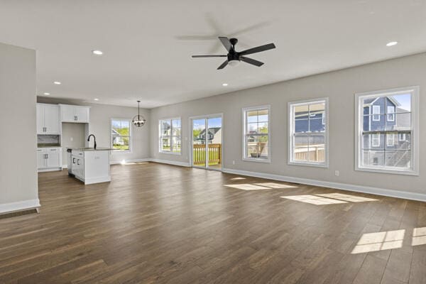 unfurnished living room featuring dark wood-style floors, recessed lighting, a sink, a ceiling fan, and baseboards