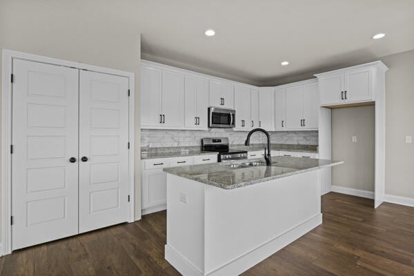 kitchen with appliances with stainless steel finishes, dark wood-style flooring, white cabinetry, and a sink