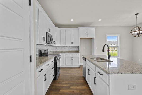 kitchen with white cabinetry, decorative backsplash, a sink, appliances with stainless steel finishes, and dark wood-style floors