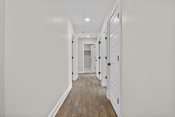 corridor featuring dark wood-type flooring, recessed lighting, and baseboards