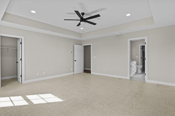 unfurnished bedroom featuring baseboards, recessed lighting, a raised ceiling, and light colored carpet