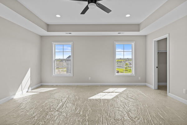 unfurnished bedroom with multiple windows, a raised ceiling, and baseboards