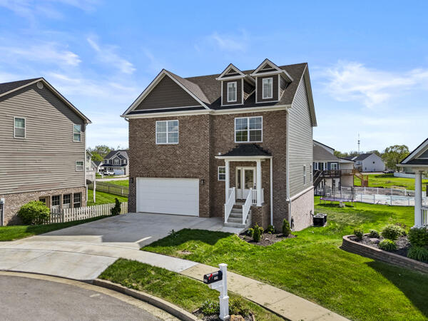 traditional-style house with brick siding, an attached garage, concrete driveway, and fence