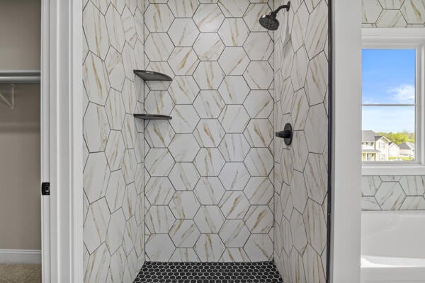 full bathroom with a tile shower, a bathtub, and plenty of natural light