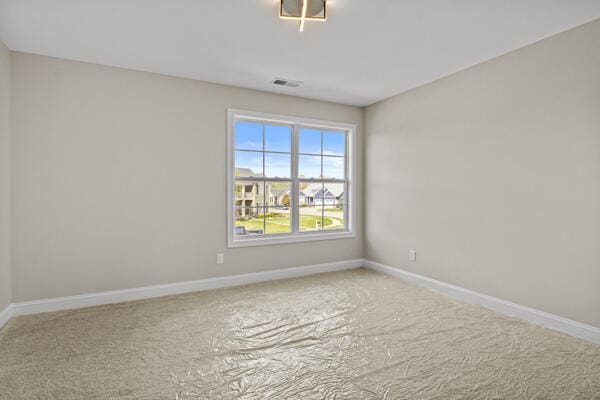 carpeted spare room with baseboards and visible vents