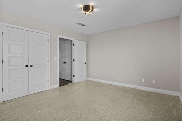 unfurnished bedroom with carpet, visible vents, a closet, and baseboards