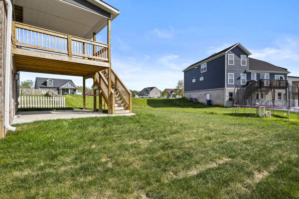 view of yard with a wooden deck, a trampoline, stairway, and a patio area