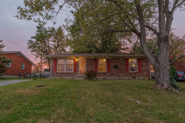 ranch-style house featuring central air condition unit and a lawn