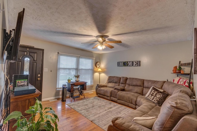 living room featuring light hardwood / wood-style floors, a textured ceiling, and ceiling fan