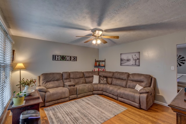 living room featuring ceiling fan, wood-type flooring, and a textured ceiling