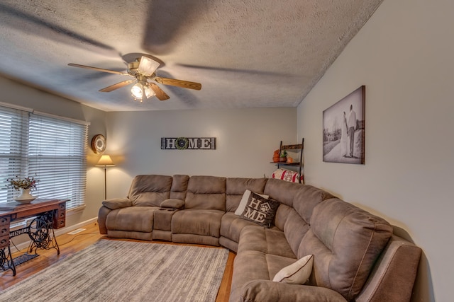 living room with a textured ceiling, wood-type flooring, and ceiling fan