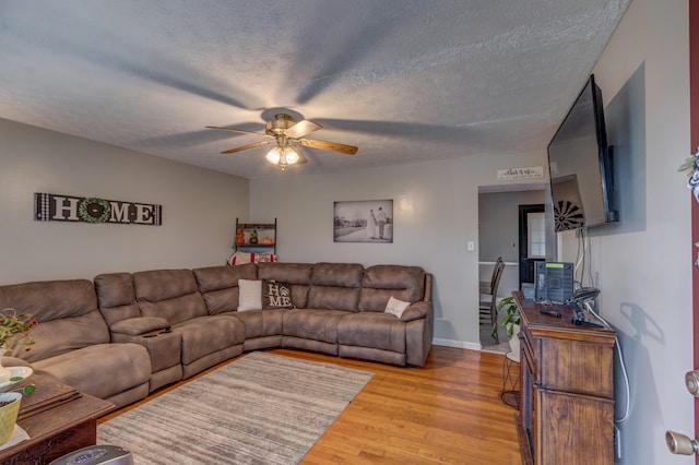 living room with light hardwood / wood-style floors, a textured ceiling, and ceiling fan