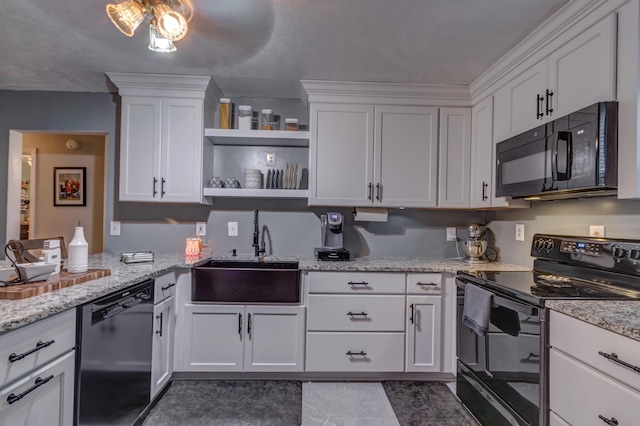 kitchen with light stone counters, black appliances, sink, and white cabinets