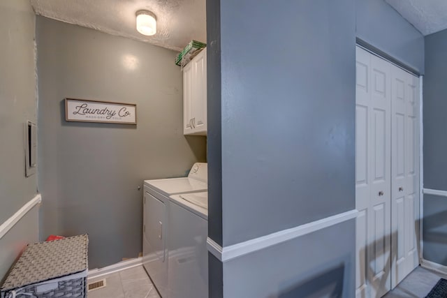 washroom featuring cabinets, light tile patterned flooring, and washer and clothes dryer