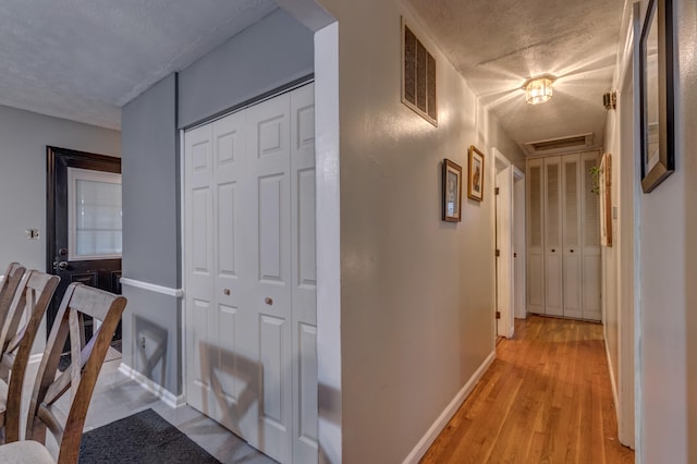 hallway featuring light hardwood / wood-style floors and a textured ceiling