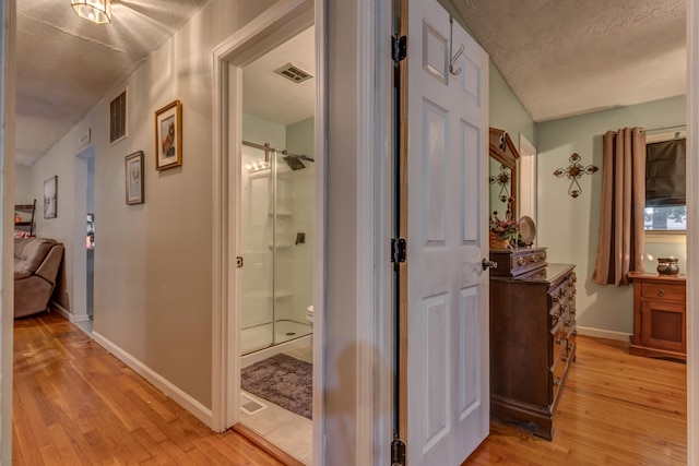 corridor featuring light hardwood / wood-style floors and a textured ceiling