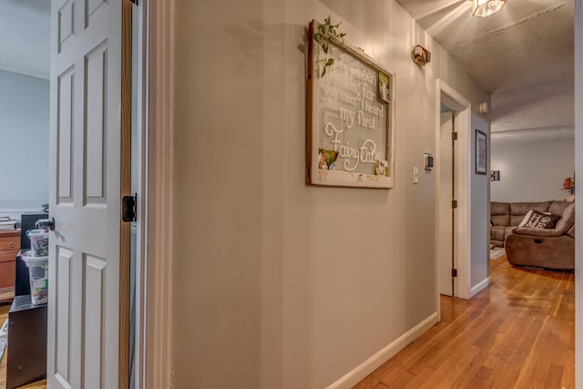 hall with light hardwood / wood-style flooring and a textured ceiling