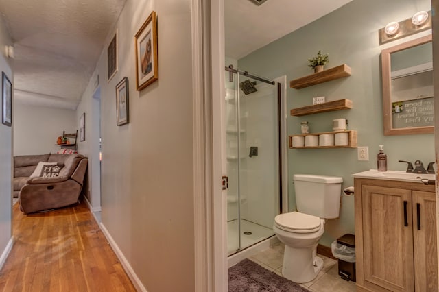 bathroom featuring a textured ceiling, hardwood / wood-style floors, toilet, walk in shower, and vanity