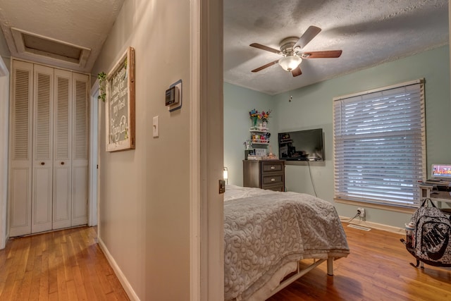 bedroom with ceiling fan, a textured ceiling, and light hardwood / wood-style floors