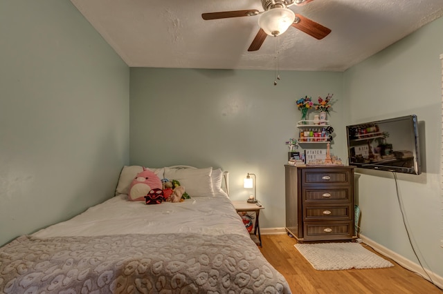 bedroom featuring light hardwood / wood-style floors, a textured ceiling, and ceiling fan