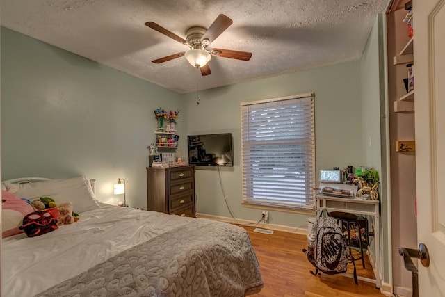 bedroom featuring light hardwood / wood-style flooring, a textured ceiling, and ceiling fan