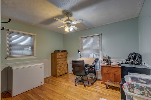 office featuring a textured ceiling, light wood-type flooring, and ceiling fan