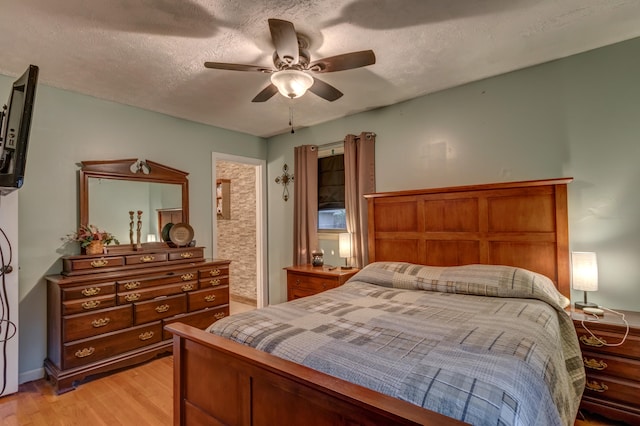 bedroom with light hardwood / wood-style floors, a textured ceiling, and ceiling fan