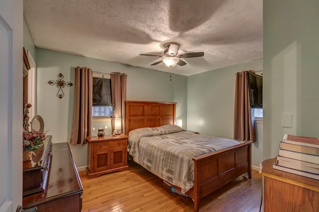 bedroom with light hardwood / wood-style floors, a textured ceiling, and ceiling fan