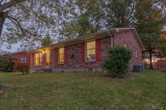 ranch-style house with central air condition unit and a lawn