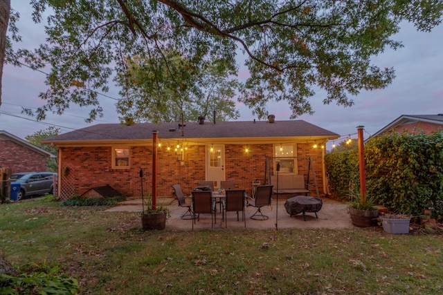 back house at dusk with a yard, a patio area, and a fire pit