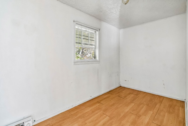 unfurnished room with hardwood / wood-style flooring and a textured ceiling