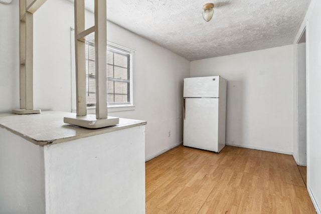 kitchen featuring white refrigerator, light wood-type flooring, and a textured ceiling